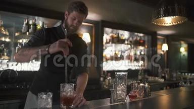 漂亮的胡子酒保把朗姆酒和冰块和长金属棒混合在玻璃杯里。 现代酒吧酒吧的酒吧男招待